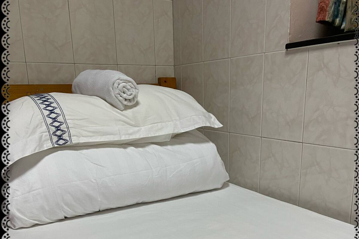 A neatly made bed with white linens and a decorative pillow.