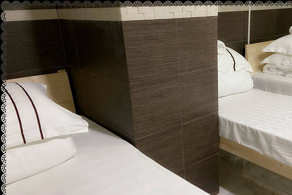 A hotel room with two single beds, dark wood headboards, and a tiled wall.