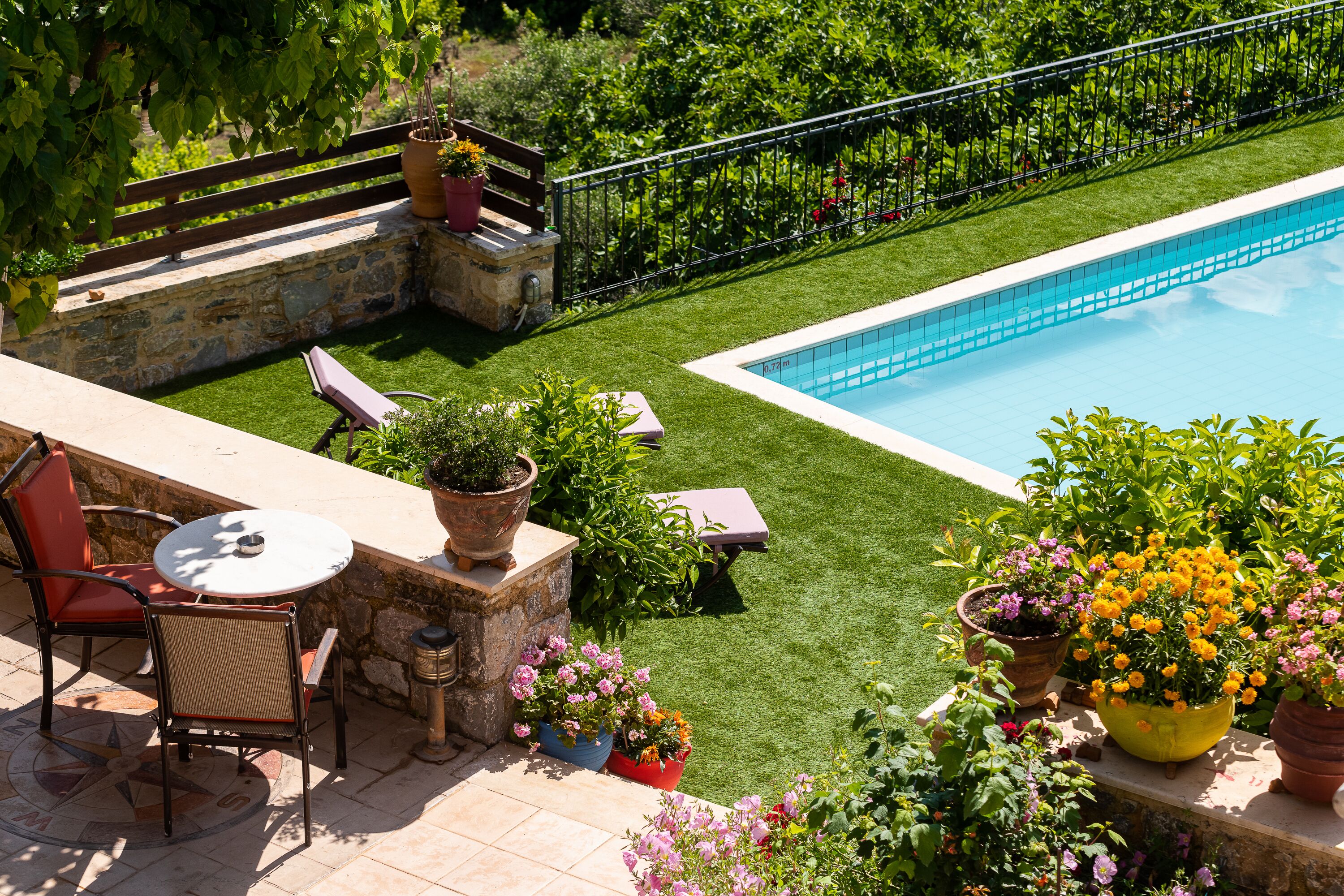 Un patio con piscina, mobiliario exterior y plantas en macetas.