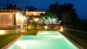 Une piscine avec un bâtiment en pierre en arrière-plan, un espace couvert avec des chaises et une vue sur le paysage environnant.