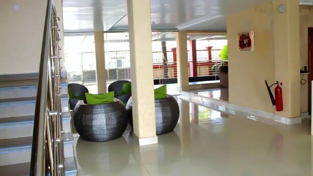 A spacious lobby with a high ceiling, a staircase, and a fire extinguisher mounted on the wall. - Premium Studio (Obuasi)
