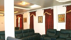A living room with dark leather sofas, a coffee table, red curtains, and framed artwork on the walls. - Premium Studio (Obuasi)