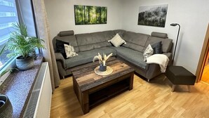 Ein modernes Wohnzimmer mit einem grauen Ecksofa, einem Holztisch und zwei Wandbildern.