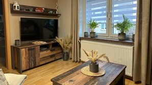 Ein gemütliches Wohnzimmer mit einer Holzeinrichtungsanlage, einem Flachbildfernseher, einem Holztisch und einem Fenster mit Vorhängen.
