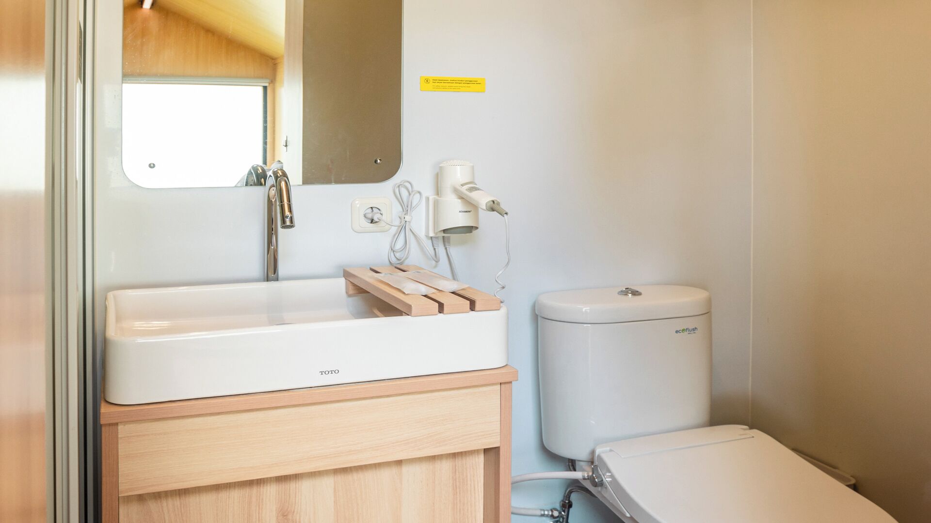 A bathroom with a white sink, a mirror, a toilet, and a shower area.