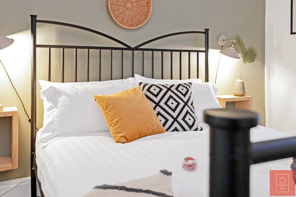 Relax in this stylish bedroom with a comfortable bed, bedside table, and potted plant.