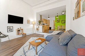 Relax in this stylish living room with a large sofa, flat-screen TV, and dining area.
