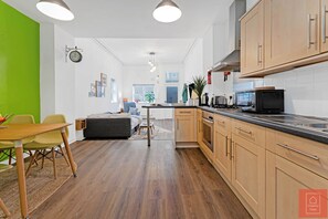 Enjoy meals in the kitchen with a stainless steel range hood and a wooden table for dining.