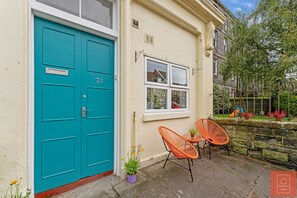 Welcome to a charming single-story residence with a vibrant turquoise door and a cozy outdoor seating area.