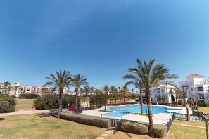 A resort with a swimming pool, palm trees, and a clear blue sky. - Beautiful apartment overlooking the pool- MO2411LT (La Torre Golf Resort)