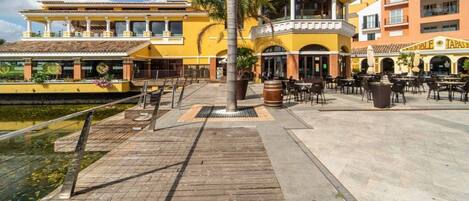 Un patio de hotel con mobiliario exterior, una palmera y una fuente de agua.