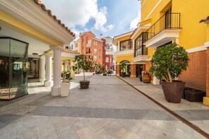A pedestrian street with buildings, outdoor seating, and potted plants. - Beautiful apartment overlooking the pool- MO2411LT (La Torre Golf Resort)