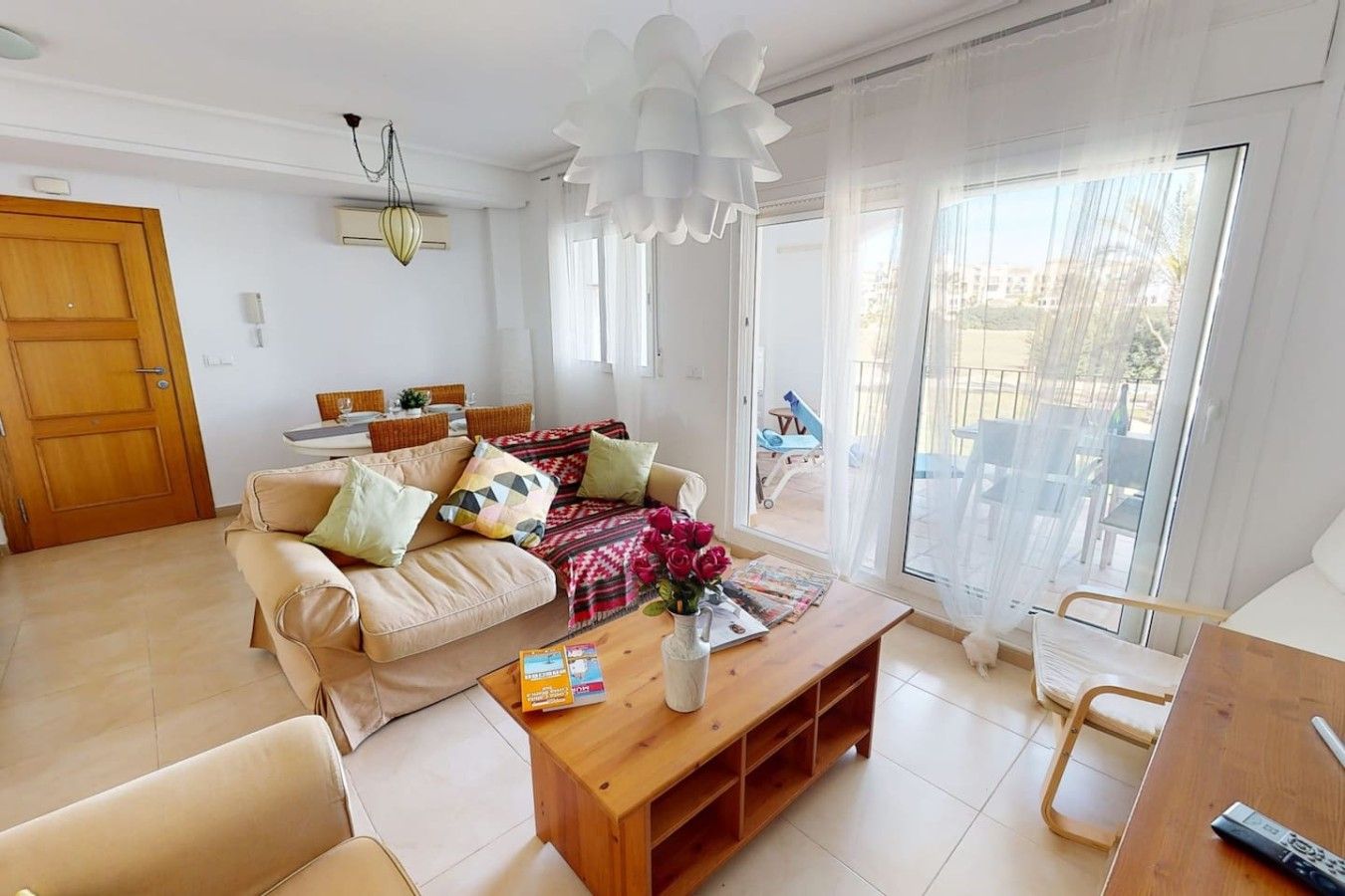 A living room with a sofa, coffee table, and a dining area with chairs.
