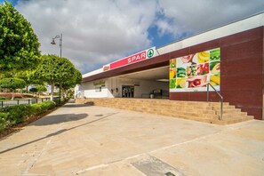 A supermarket entrance with a ramp leading up to the door, surrounded by greenery and a clear sky. - Beautiful apartment overlooking the pool- MO2411LT (La Torre Golf Resort)