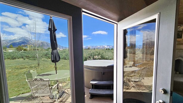 Una stanza con una porta scorrevole in vetro che dà su un patio con tavolo, sedie e zona riparata.