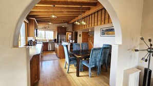 Una cucina con travi in legno, una zona pranzo con sedie blu e un'ampia finestra.