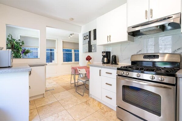 A modern kitchen with white cabinets, a stainless steel stove, and a tiled floor.