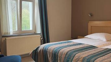 Ett hotellrum med en säng, ett runt bord och ett fönster med gardiner.
