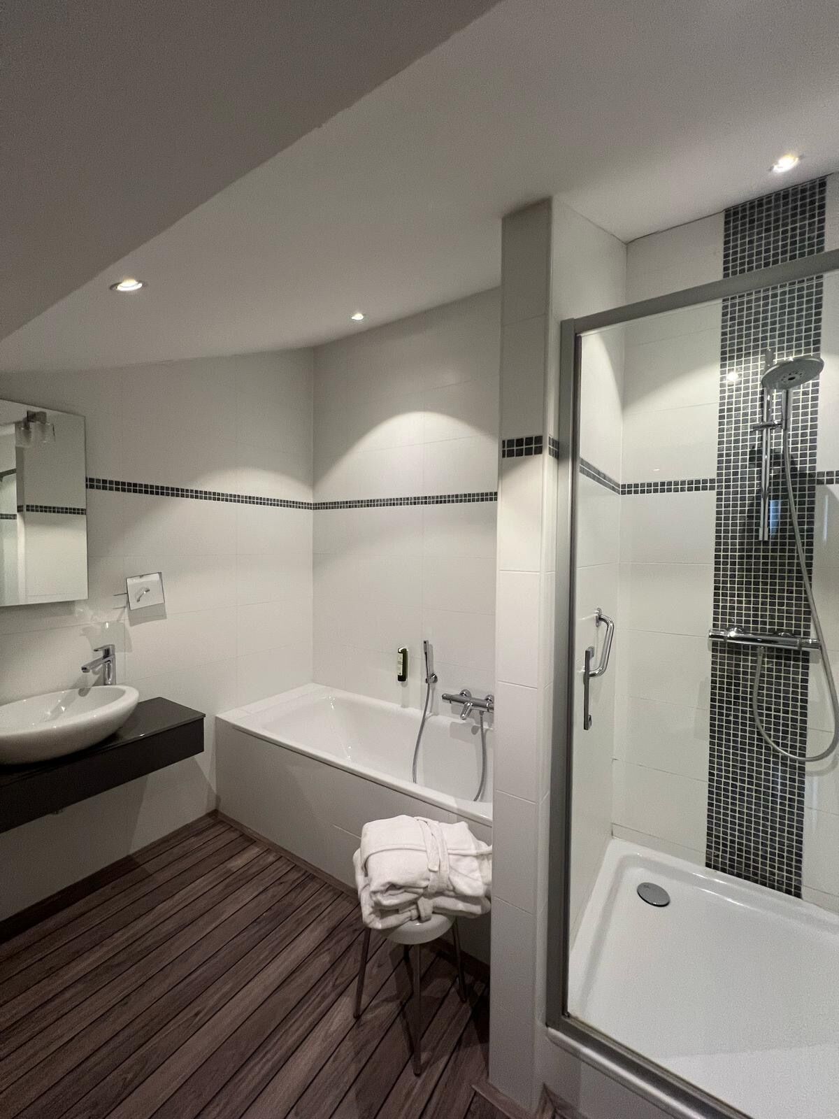 A modern bathroom with a bathtub, a shower, and a sink.