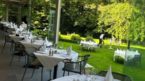 An outdoor dining area with tables set for a meal, surrounded by a lush garden and a clear view of the trees. - Moulin de Daverdisse (Daverdisse)