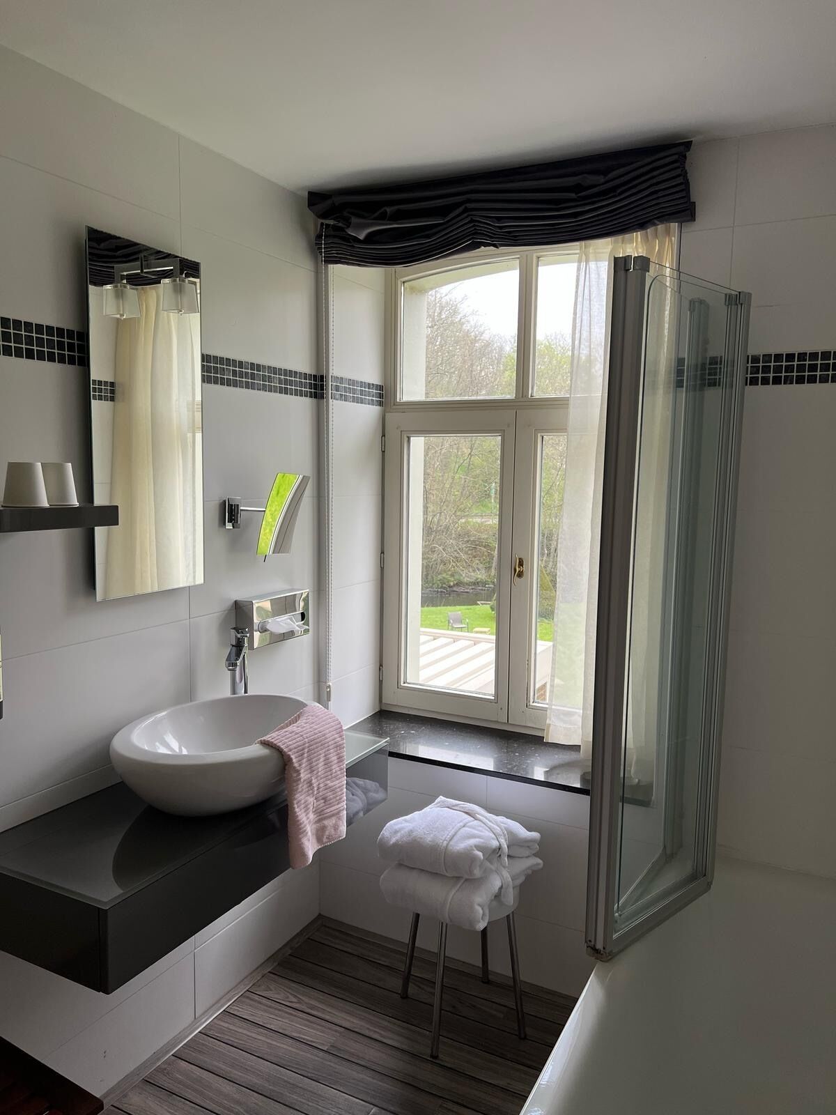 A modern bathroom with a large window, a shower, and a sink.