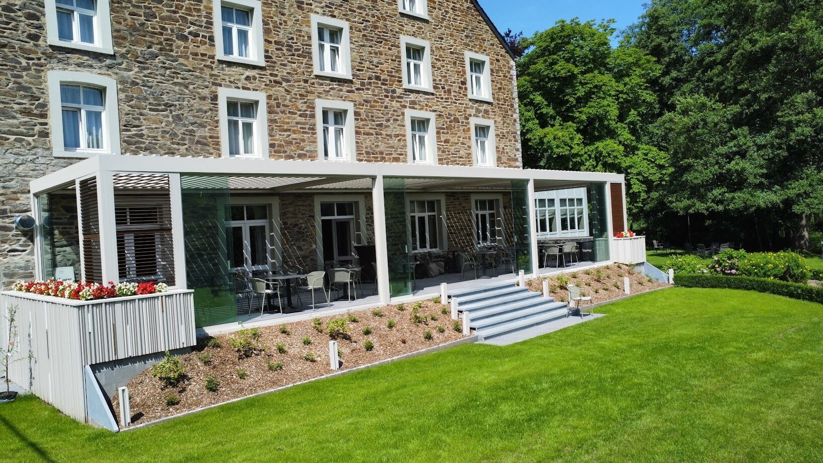 A stone building with a covered outdoor seating area and a grassy lawn.