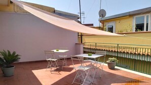 A small patio with a table and chairs, a potted plant, and a sunshade. - Essences of Sicily Apartment (Letojanni)
