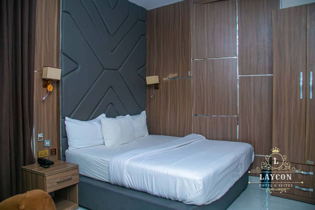 Ett hotellrum med en stor säng, en garderob i trä och två sänglampor.