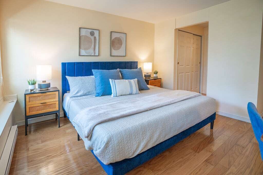 A bedroom with a large bed, two bedside tables, a wardrobe, and two framed pictures on the wall.