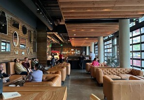 A spacious indoor area with leather seating, wooden beams, and large windows.