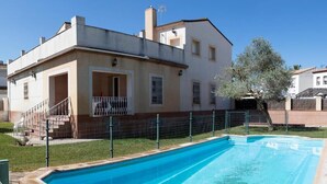 Una casa a due piani con piscina, patio coperto e cortile recintato.