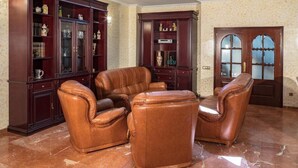 Una stanza con un divano in pelle marrone, mobili scuri in legno con ante in vetro e un pavimento in marmo.