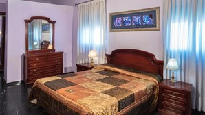 Una camera da letto con un letto grande, una cassettiera, un comodino, uno specchio e un'opera d'arte incorniciata appesa al muro.
