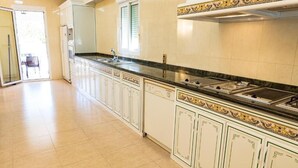 Una cucina con un lungo piano di lavoro, mobili bianchi e una finestra.