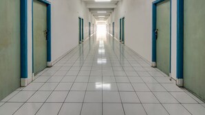 A long, narrow hallway with white tiled floors and blue-framed doors on both sides. - Spot ON 90964 Hotel Margadana (Tegal)