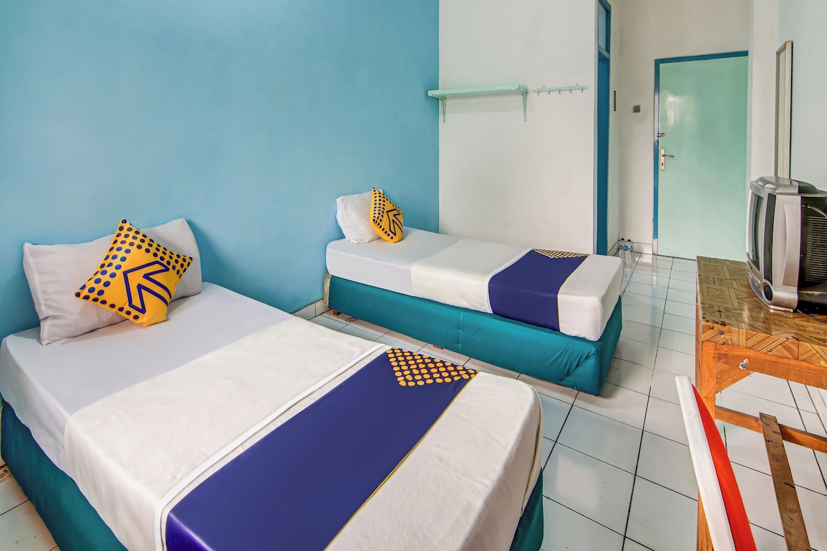 Una habitación de hotel con dos camas, televisión y una puerta.