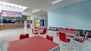 A hotel lobby with red tables and chairs, a sign for a vaccination and mask area, and a 'Spot On' sign. - Spot ON 90964 Hotel Margadana (Tegal)