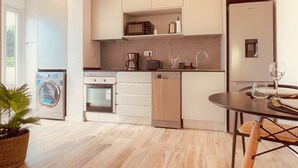 Une cuisine moderne équipée d’un lave-vaisselle, d’un four, d’un four à micro-ondes et d’une machine à café. Un coin repas avec une table et des chaises est également à disposition.