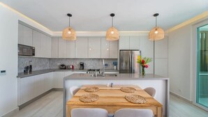 Une cuisine moderne avec des meubles blancs, un îlot central et des luminaires suspendus.