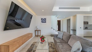 Un salon moderne avec un téléviseur à écran plat, un canapé, une table basse et un banc en bois.