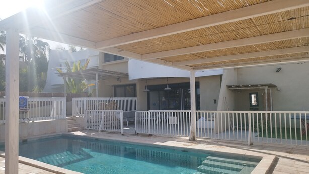 A swimming pool with a wooden deck and white railing. - YalaRent Cliff side villa - private pool (Eilat)