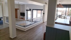 A spacious living area with a balcony, a dining area with outdoor seating, and a TV in the background. - YalaRent Cliff side villa - private pool (Eilat)