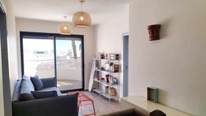 A modern living room with a sofa, a bookshelf, and a dining table. - YalaRent Cliff side villa - private pool (Eilat)
