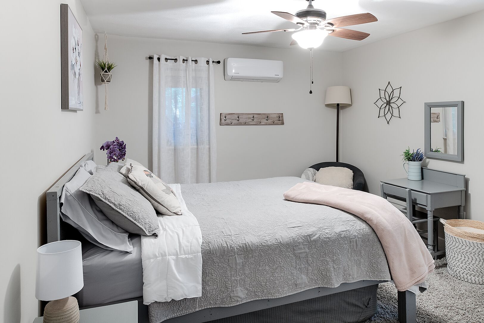 Un dormitorio con cama, mesita de noche, lámpara y ventilador de techo.