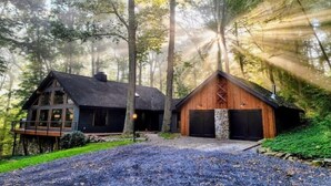 Una cabaña con una terraza amplia y cimientos de piedra, rodeada de un bosque.