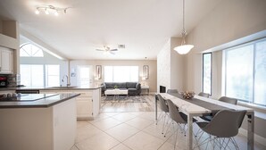 A modern kitchen with a central island, a dining area with a long table and chairs, and a living room with a sofa and a fireplace. - Stylish 4 Bed, 3 Bath in Henderson/Green Valley! (Henderson)