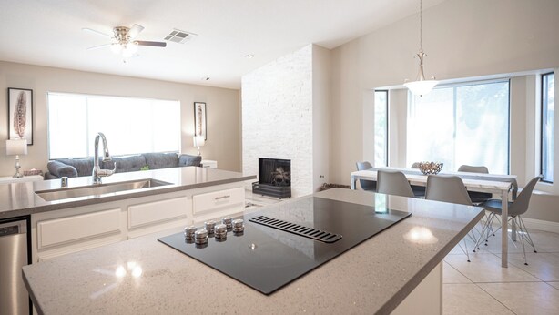 A modern kitchen with a central island, a dining area with a table and chairs, and a built-in fireplace. - Stylish 4 Bed, 3 Bath in Henderson/Green Valley! (Henderson)