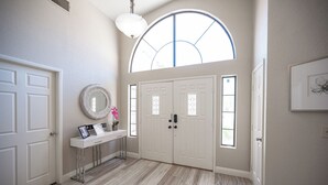 A hallway with a large arched window, white doors, and a console table with a mirror and decorative items. - Stylish 4 Bed, 3 Bath in Henderson/Green Valley! (Henderson)
