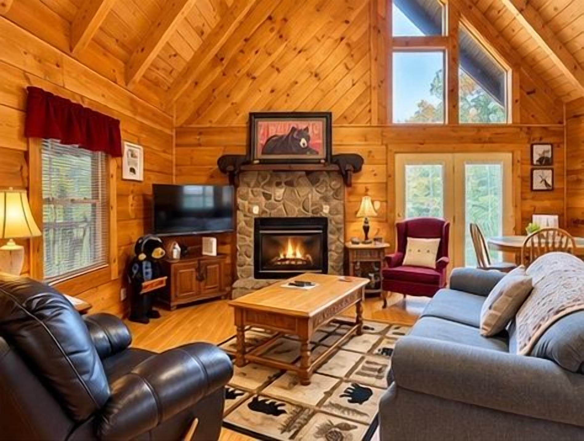A log cabin interior with a fireplace, leather furniture, and a television.