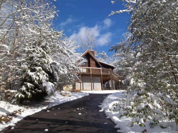 Une cabane en bois dotée d’un balcon, entourée d’arbres couverts de neige.